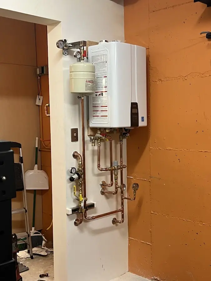 Plumbing technician inspecting water heater connections in Rome